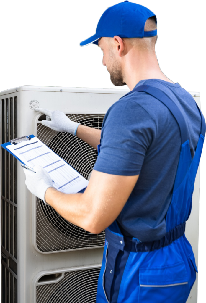An HVAC tech in a blue shirt and hat holds a clipboard while inspecting an air conditioning unit.